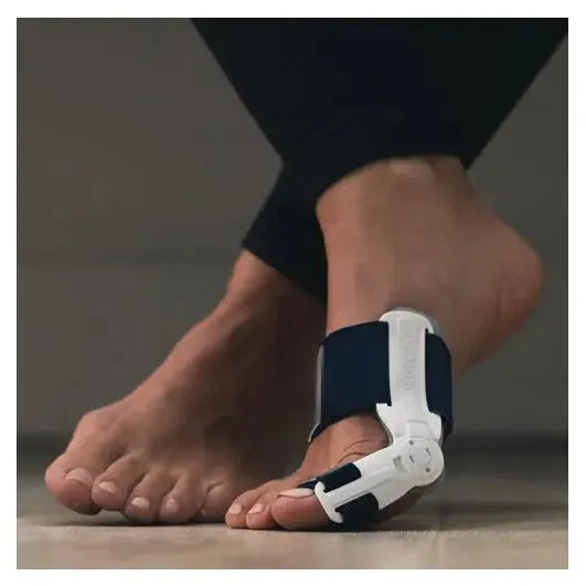Person wearing a white and black foot orthotic device on a neutral background - okotoks hc pharmacy