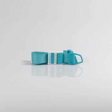 A turquoise blue adjustable strap with a white plastic buckle, displayed on a clean white reflective surface. - okotoks hc pharmacy