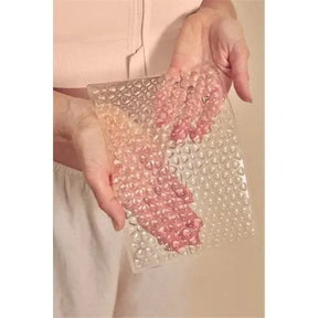 Hand holding a Amoena Large Lymph Flow Pressure Pad  against a beige background - okotoks hc pharmacy