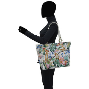 Person holding a floral-patterned handbag on a white background - okotoks hc pharmacy