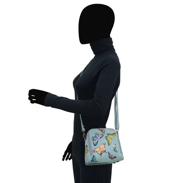 Person wearing a dark outfit with a light blue bag featuring butterfly designs on a white background - okotoks hc pharmacy