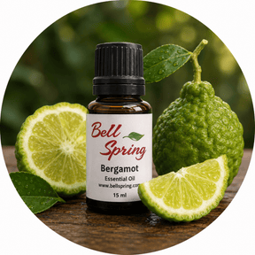 Bell Spring Bergamot essential oil bottle with a black cap, surrounded by fresh bergamot fruits and lime slices on a wooden surface with a blurred green background. - okotoks hc pharmacy