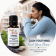 Bell Spring Calming essential oil blend bottle shown beside a woman in a light blue sweater in a softly blurred indoor setting. Text on the image reads 'CALM YOUR MIND. - okotoks hc pharmacy