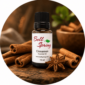 A 15 ml bottle of Bell Spring Cinnamon Essential Oil surrounded by cinnamon sticks, star anise, and a wooden bowl in a circular composition on a rustic wooden background. - okotoks hc pharmacy