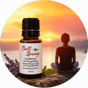 A 15 ml bottle of Bell Spring Equilibrium Yin Yang Blend essential oil placed in front of a circular background graphic showing a woman meditating at sunset with lavender sprigs and mint leaves. - okotoks hc pharmacy
