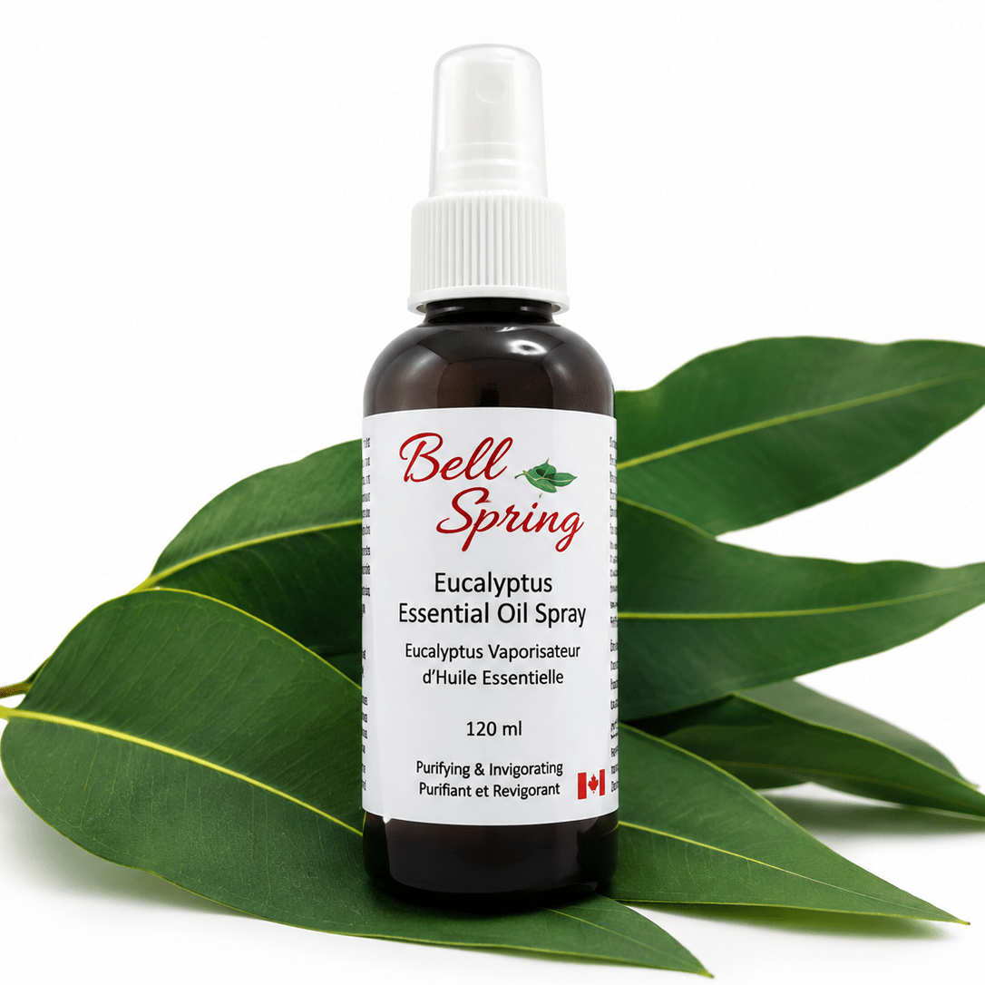 Bell Spring Eucalyptus Essential Oil Spray in a 120 ml amber glass bottle with a white spray cap, displayed on green eucalyptus leaves against a white background. - okotoks hc pharmacy