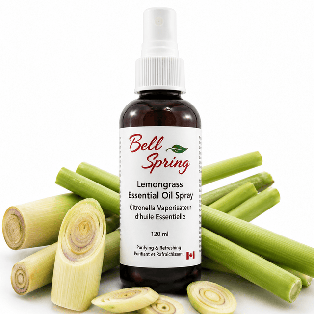 Bell Spring Lemongrass Essential Oil Spray bottle in amber glass with a white spray cap, surrounded by fresh green lemongrass stalks and sliced pieces on a white background. - okotoks hc pharmacy