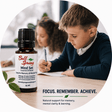 A 10 mL bottle of Bell Spring Mind Set essential oil blend is shown in the foreground, with a boy studying at a desk in a softly blurred classroom background. The image is framed in a circular graphic with the text 'FOCUS. - okotoks hc pharmacy