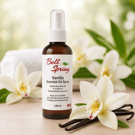 Bell Spring Vanilla Essential Oil Spray in a 120 ml amber glass bottle with a white spray cap, styled on a wooden surface with white orchids and vanilla beans. - okotoks hc pharmacy