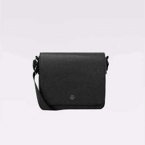 A black pebbled leather crossbody bag with a small circular metal logo emblem on the front flap, displayed against a clean light gray background. - okotoks hc pharmacy