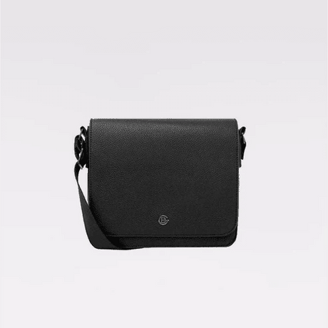 A black pebbled leather crossbody bag with a small circular metal logo emblem on the front flap, displayed against a clean light gray background. - okotoks hc pharmacy