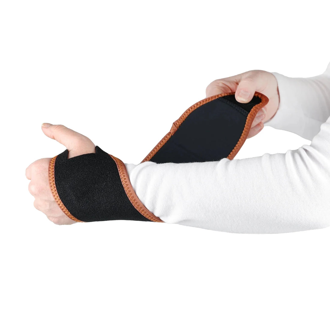 Hand wearing a black wrist support with brown trim on a white background - okotoks hc pharmacy