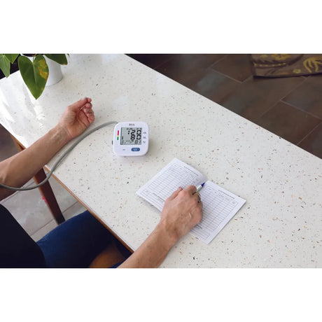 Person taking their blood pressure and noting the reading on a piece of paper. - okotoks hc pharmacy