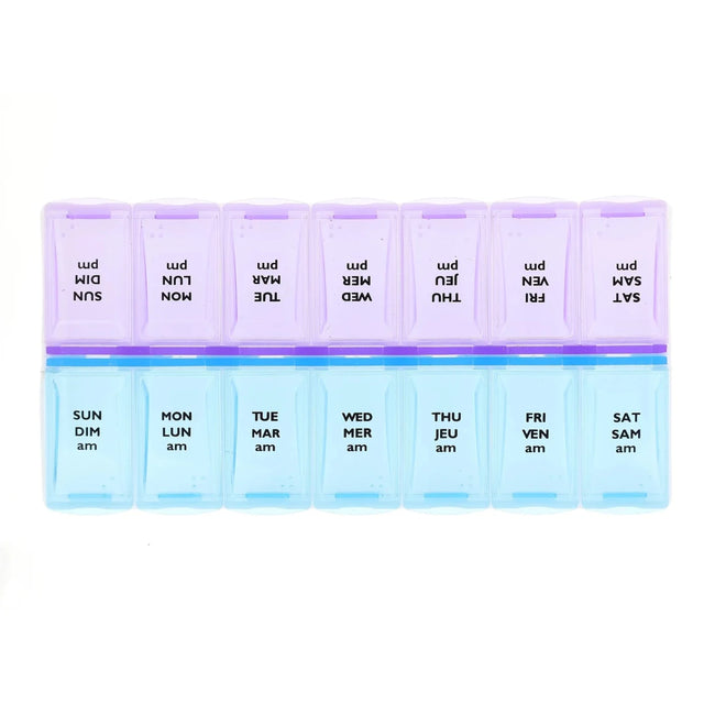 A 7-day weekly pill organizer with translucent plastic compartments. The top row is light purple with black text showing reversed days of the week (SUN, MON, etc. - okotoks hc pharmacy