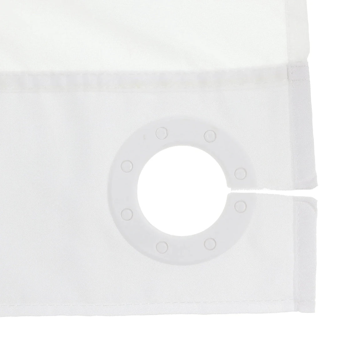 Close-up of a white curtain panel showing the fabric texture, stitched hem, and a circular grommet ring on the corner. - okotoks hc pharmacy