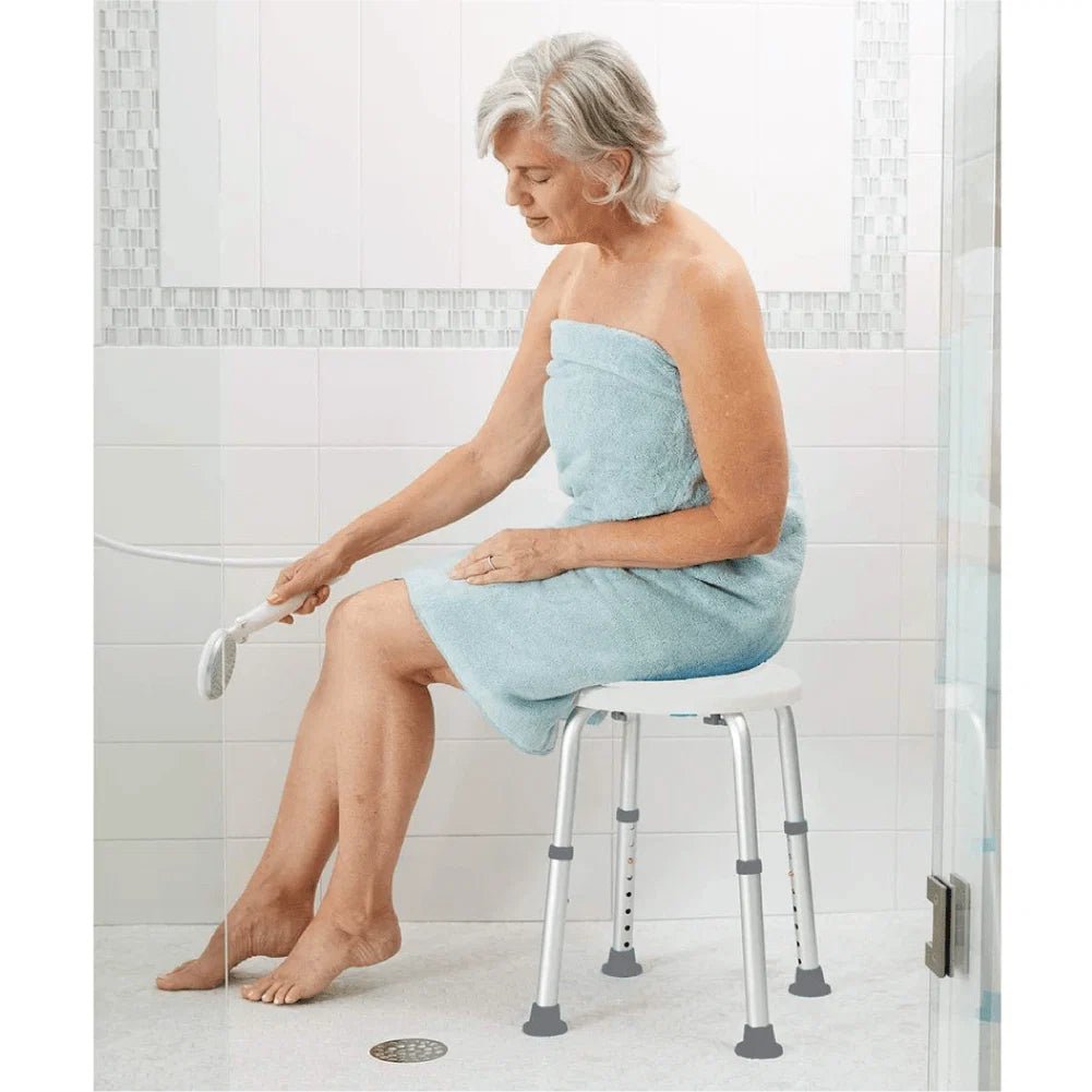 Woman sitting on a shower chair with a bath towel wrapped around her, holding a loofah.- okotoks hc pharmacy