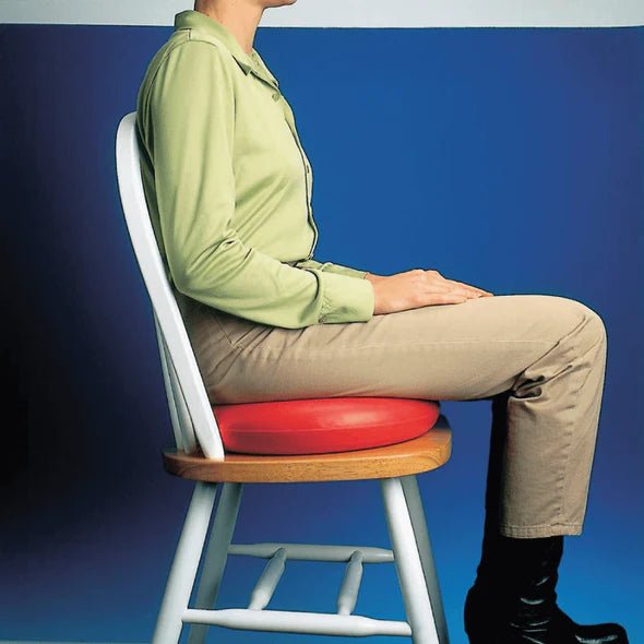 Person sitting on a stool with a red cushion against a blue background - okotoks hc pharmacy