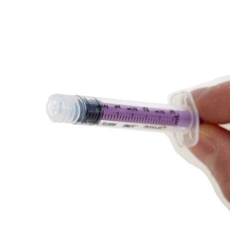 Hand holding a syringe with a clear liquid on a white background - okotoks hc pharmacy