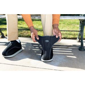 Person holding a black shoe outdoors on a sunny day - okotoks hc pharmacy