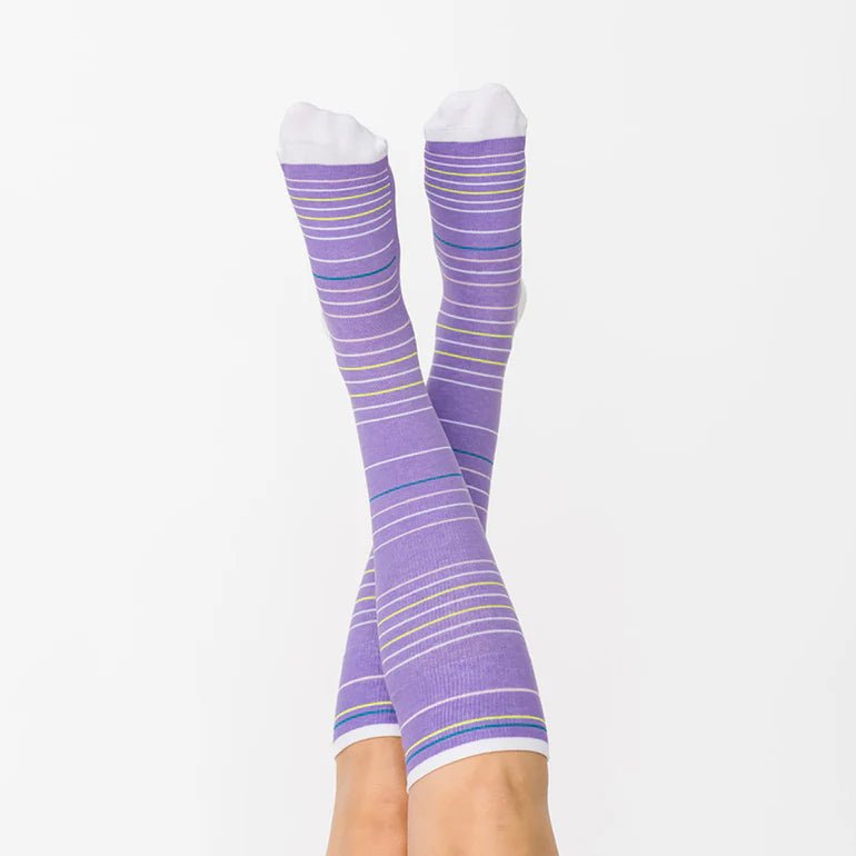 Purple striped knee-high socks with white toes and heels, worn on crossed legs against a plain white background. - okotoks hc pharmacy