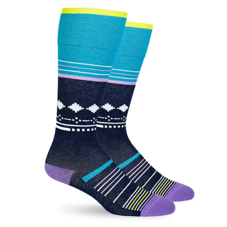 A pair of crew socks with a colorful geometric pattern, featuring a teal upper leg section, a navy blue lower leg section with white diamond motifs, and purple, yellow, and blue accents on the foot. - okotoks hc pharmacy