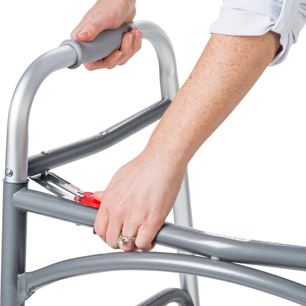 Person using a silver walker with red brake handle on a white background - okotoks hc pharmacy
