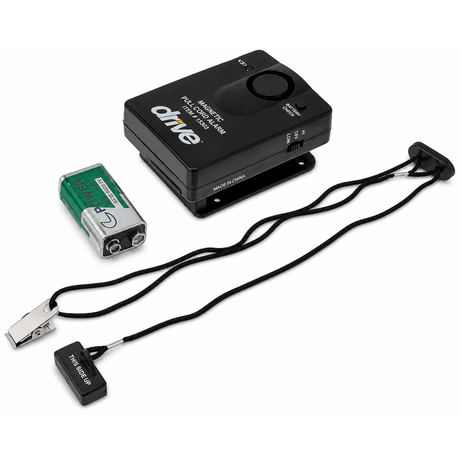 Drive Medical Magnetic Pull Cord Alarm, featuring a black control box, a green and silver 9V battery, a black clip, and a black wrist strap with a transmitter end, all on a white background. - okotoks hc pharmacy