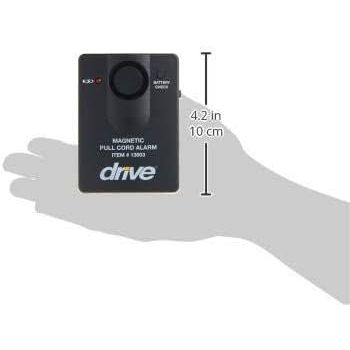 A small black magnetic full-cord alarm with the brand name 'drive' printed in white on the front, shown resting on a gray hand silhouette for scale. White measurement text and arrows indicate 4. - okotoks hc pharmacy