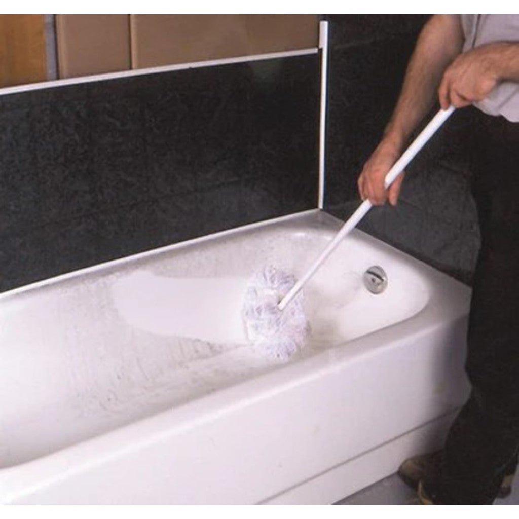 A person using a long-handled white scrubber to clean a white bathtub with soapy water inside a tiled bathroom. - okotoks hc pharmacy