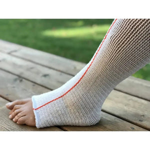 White knit sock with orange trim on a child's foot, sitting on a wooden surface outdoors. - okotoks hc pharmacy