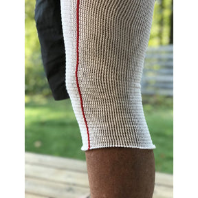 Close-up of a person wearing a white sleeve with a red stripe on a blurred outdoor background - okotoks hc pharmacy