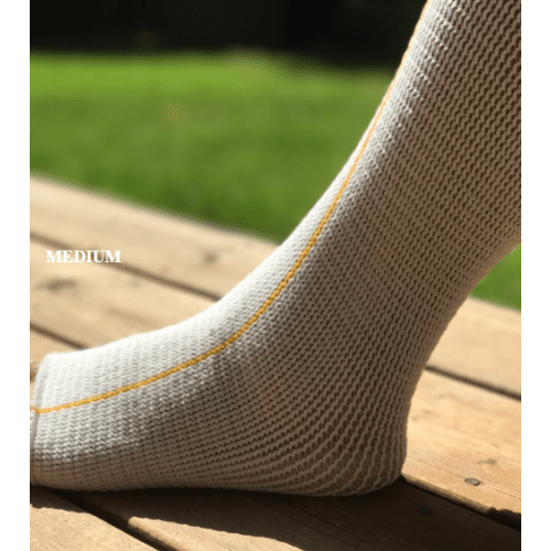Close-up of a foot wearing a gray sock with yellow stitching on a wooden surface. - okotoks hc pharmacy