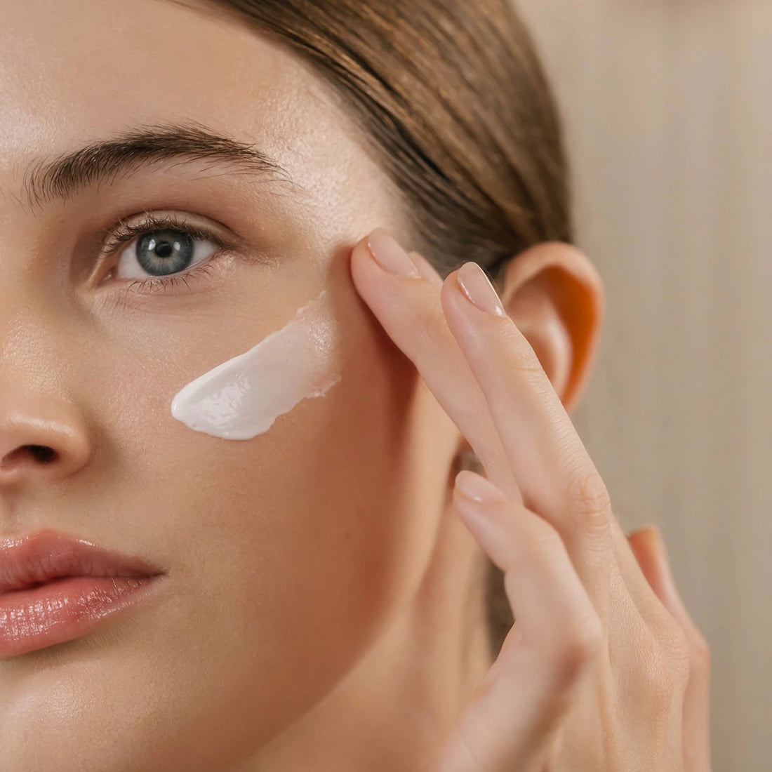 Woman applying cream to her face with a neutral background - okotoks hc pharmacy