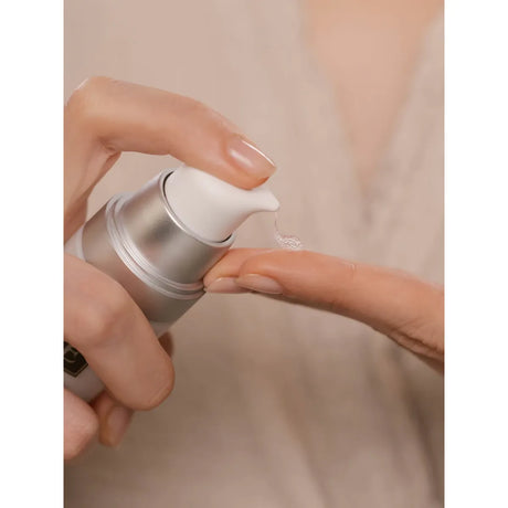 Hand holding a skincare product with a close-up of cream on a finger against a neutral background - okotoks hc pharmacy