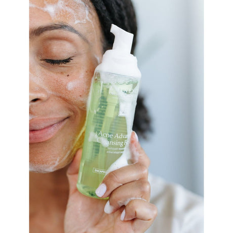 Person holding a bottle of Acne Advance Cleansing Gel with a blurred background - okotoks hc pharmacy