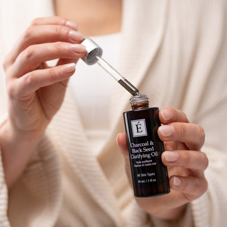 Person holding a bottle of Charcoal & Black Seed Oil with a dropper. - okotoks hc pharmacy