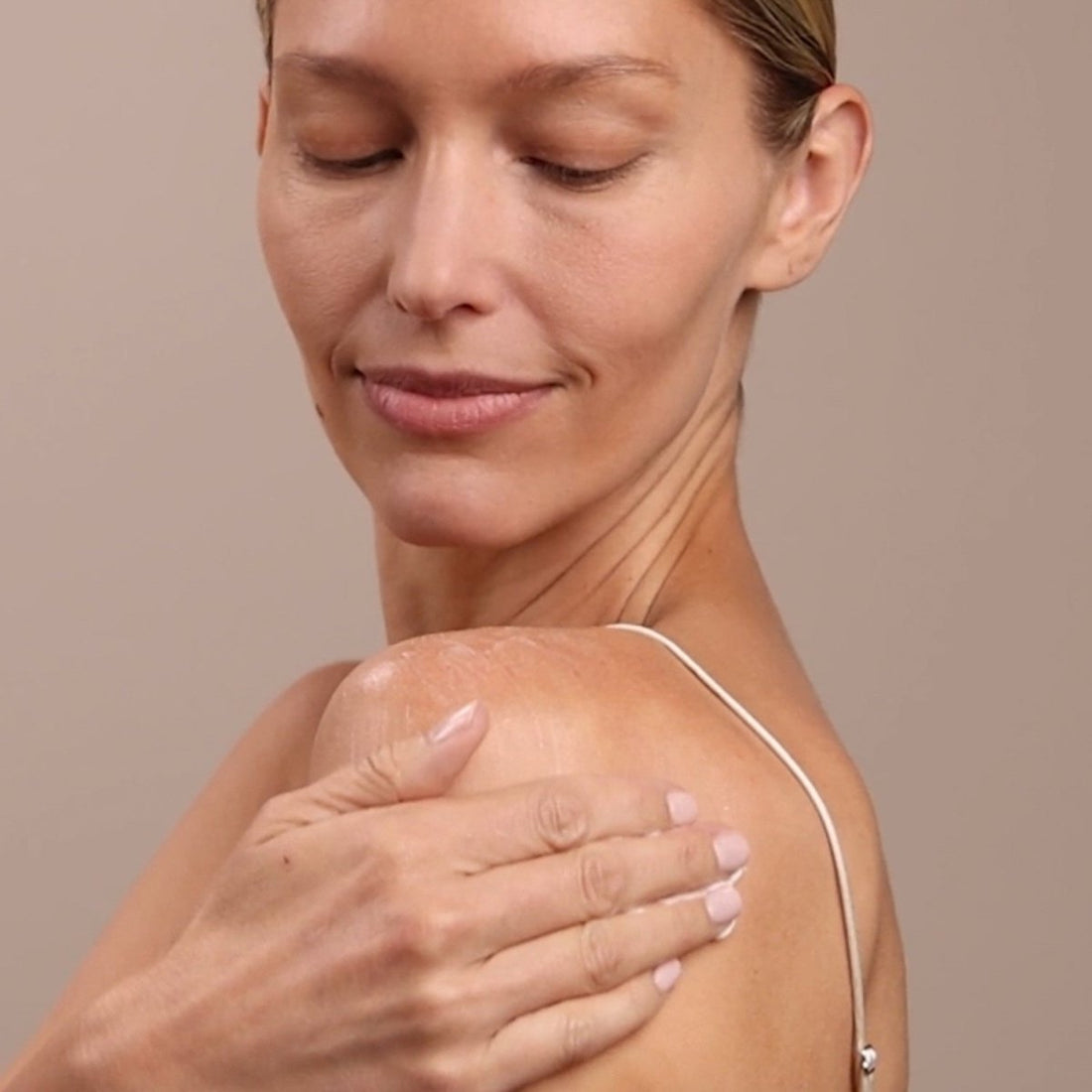 Woman touching her shoulder with a neutral background - okotoks hc pharmacy