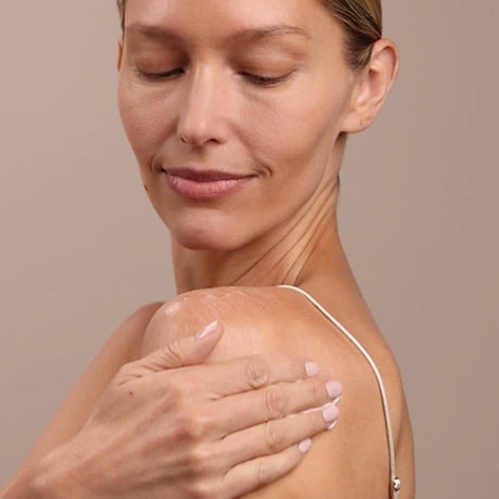 Woman touching her shoulder with a neutral background - okotoks hc pharmacy