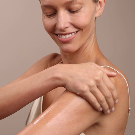 Woman with smooth skin touching her arm against a neutral background - okotoks hc pharmacy