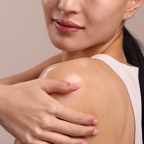 Close-up of a woman's shoulder with a hand gently touching it against a neutral background - okotoks hc pharmacy
