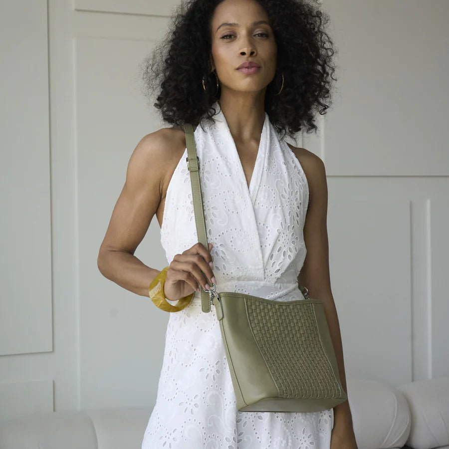 Woman holding a green handbag against a neutral background - okotoks hc pharmacy