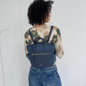 Person wearing a blue backpack with a white background - okotoks hc pharmacy