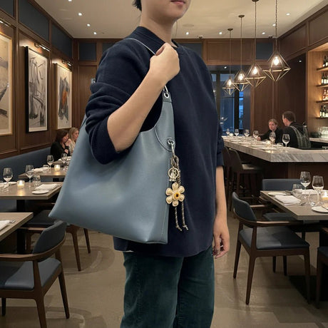 Person holding a blue handbag with a floral charm in a restaurant setting - okotoks hc pharmacy