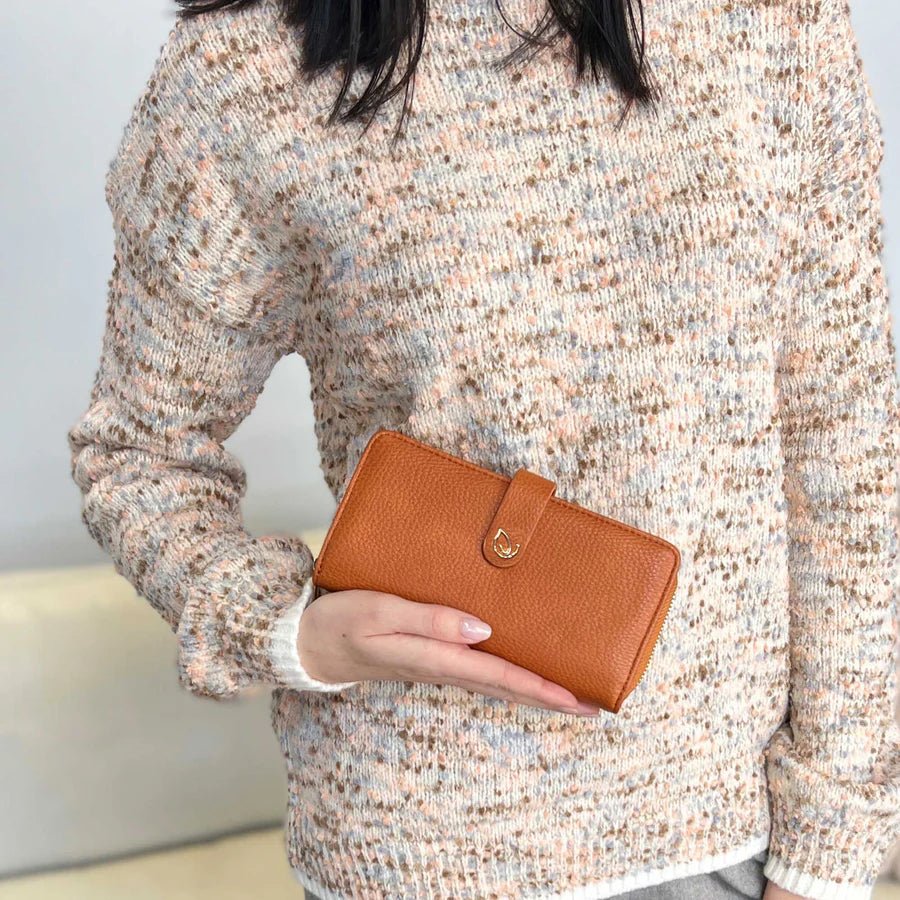 Person holding a brown wallet against a neutral background - okotoks hc pharmacy