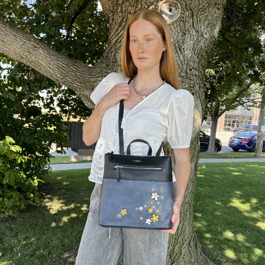 Woman holding a blue handbag with floral designs outdoors near a tree - okotoks hc pharmacy