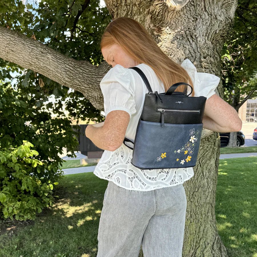 Woman with a floral-patterned backpack standing next to a tree outdoors - okotoks hc pharmacy