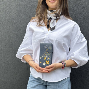 Person holding a floral-patterned wallet against a gray background - okotoks hc pharmacy