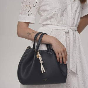 Person holding a black handbag with a white dress - okotoks hc pharmacy