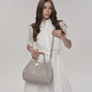 Woman holding a gray handbag against a plain background - okotoks hc pharmacy