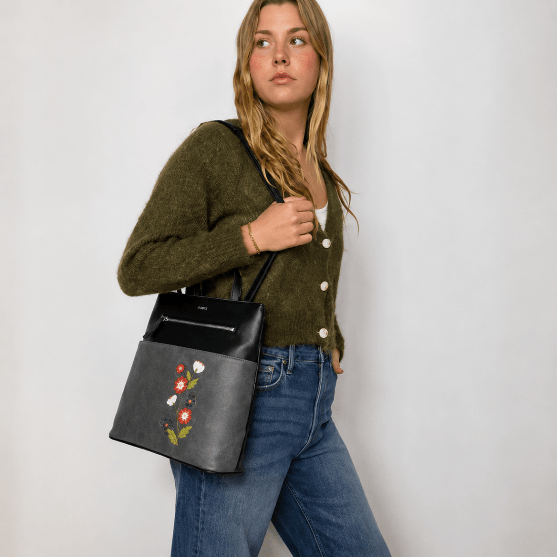Woman holding a black handbag with floral embroidery against a plain background - okotoks hc pharmacy